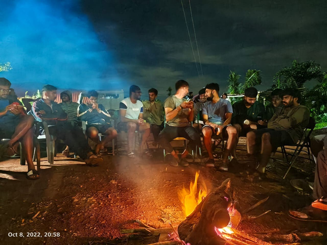 Guests sitting around a camp fire at night at Satish Mullodi Home Stay in Kudremukh